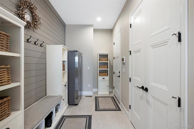 mudroom with recessed lighting, baseboards, light tile patterned floors, and wooden walls