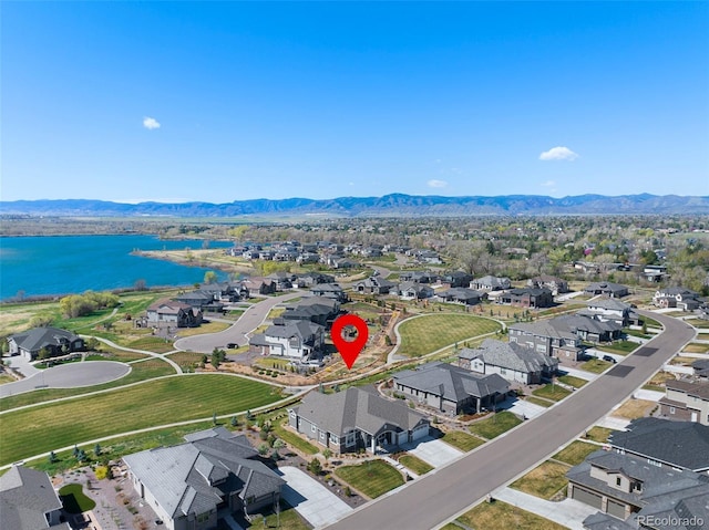 drone / aerial view with a water and mountain view and a residential view