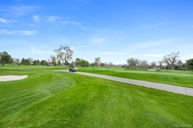 view of community featuring view of golf course and a yard