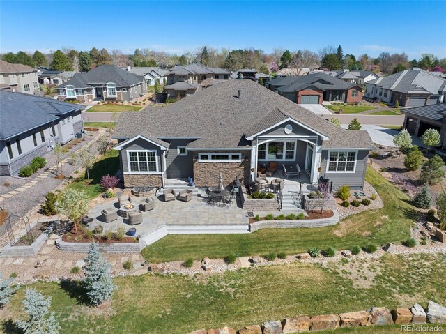 back of house with a residential view, a patio area, and stone siding