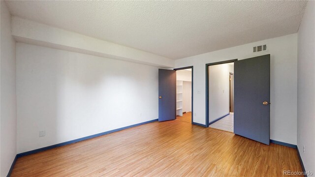 3526 S Depew St Unit 102, Lakewood, CO 80235 - unfurnished bedroom with wood finished floors, a textured ceiling, a closet, and a spacious closet