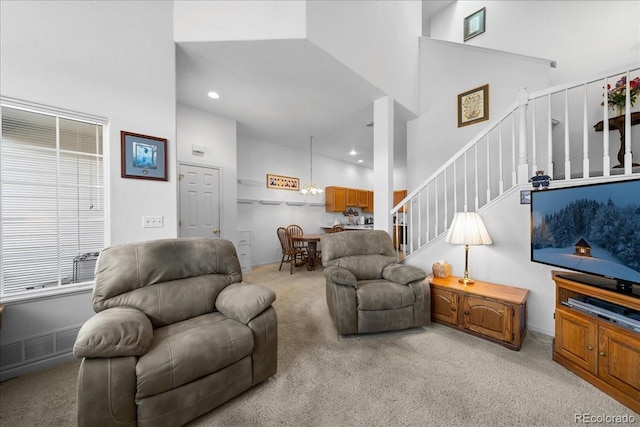 living area featuring a towering ceiling, recessed lighting, stairway, and light colored carpet