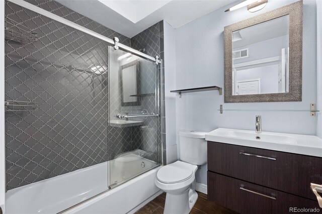 full bathroom with vanity, combined bath / shower with glass door, wood-type flooring, and toilet