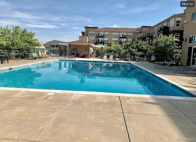 community pool with a patio area and fence