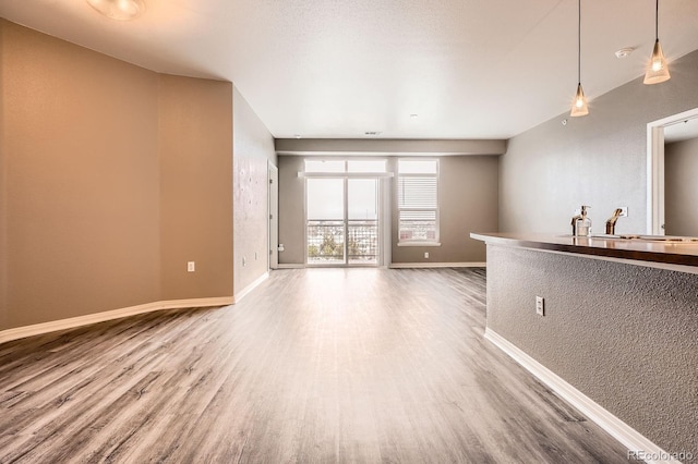 unfurnished living room featuring wood finished floors, baseboards, and a sink