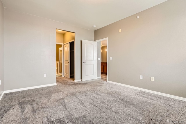 unfurnished bedroom with baseboards, carpet floors, and ensuite bathroom