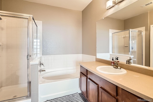 bathroom with a shower stall, a garden tub, a textured wall, and vanity