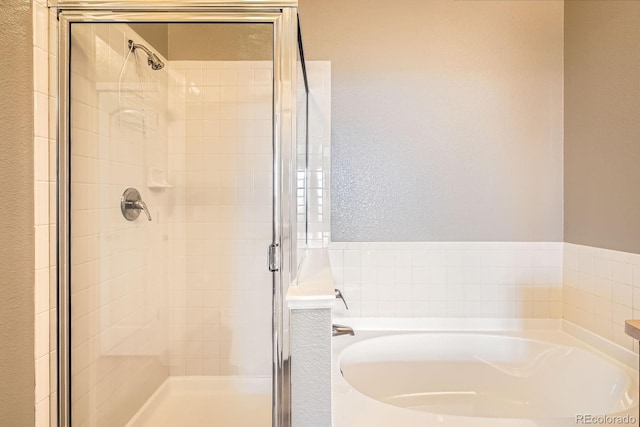 full bath featuring a bath, a shower stall, and a textured wall