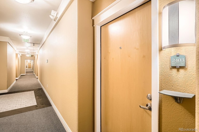 corridor with attic access, carpet, and baseboards