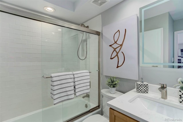 full bathroom with bath / shower combo with glass door, vanity, and toilet