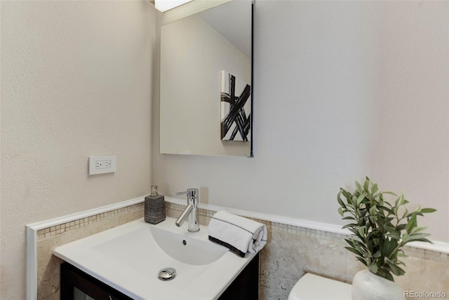 bathroom featuring vanity, tile walls, and toilet