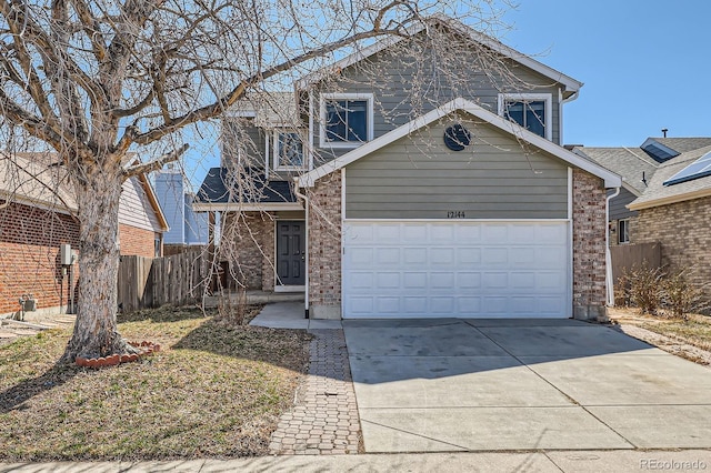 traditional-style home featuring a garage, brick siding, driveway, and fence