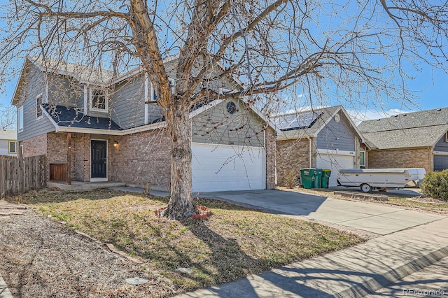 traditional-style home featuring a garage, brick siding, concrete driveway, and fence