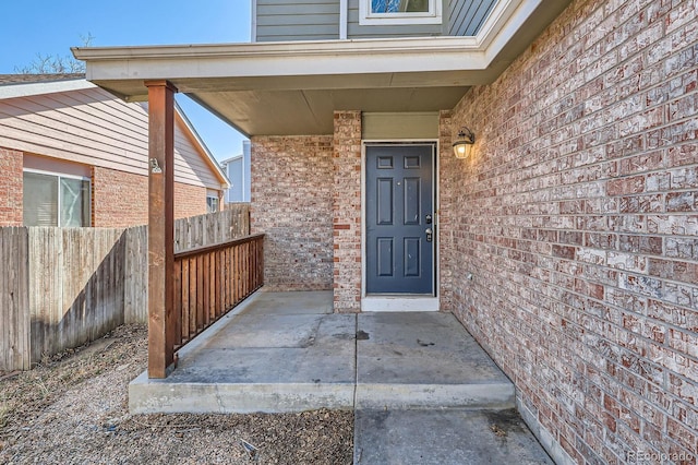 entrance to property with brick siding and fence