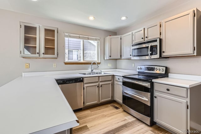 kitchen featuring light wood finished floors, a sink, recessed lighting, stainless steel appliances, and light countertops