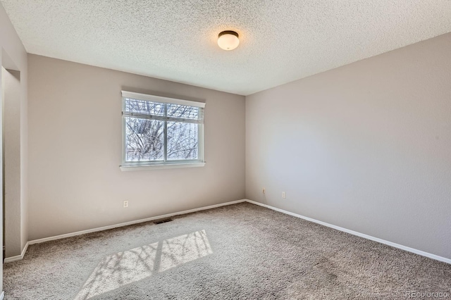 spare room with visible vents, a textured ceiling, baseboards, and carpet floors