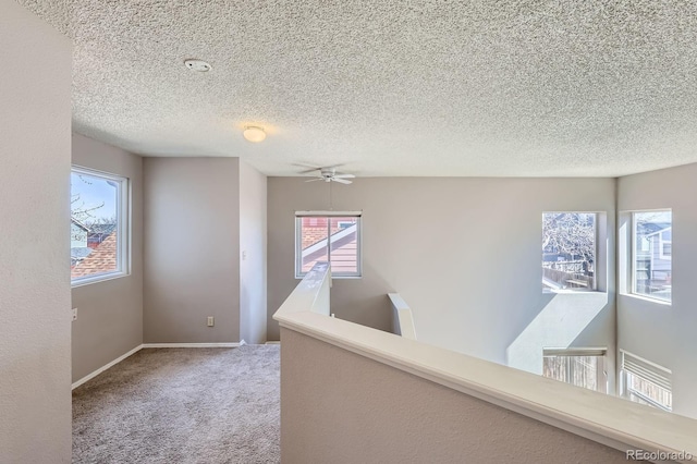 corridor featuring baseboards, a textured ceiling, and carpet flooring