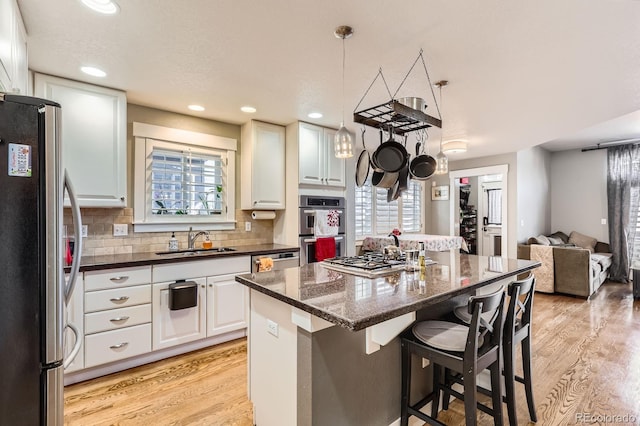 kitchen with a center island, stainless steel appliances, light wood-style floors, and a sink