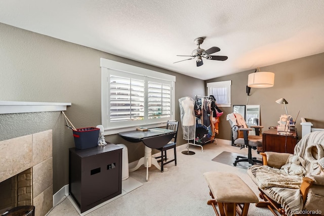 carpeted home office with vaulted ceiling, a fireplace, a textured wall, a textured ceiling, and a ceiling fan