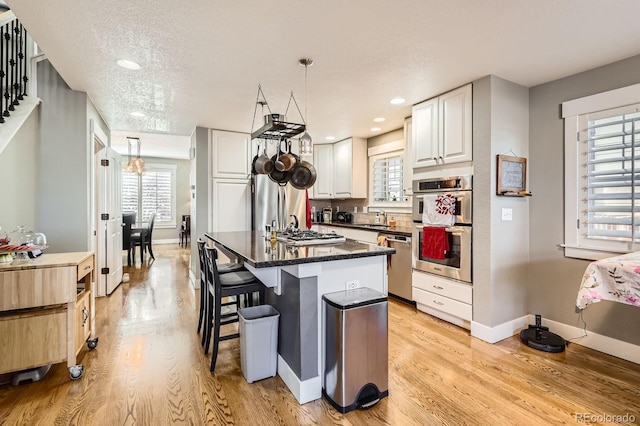 kitchen with a sink, stainless steel appliances, a kitchen bar, and light wood-style floors