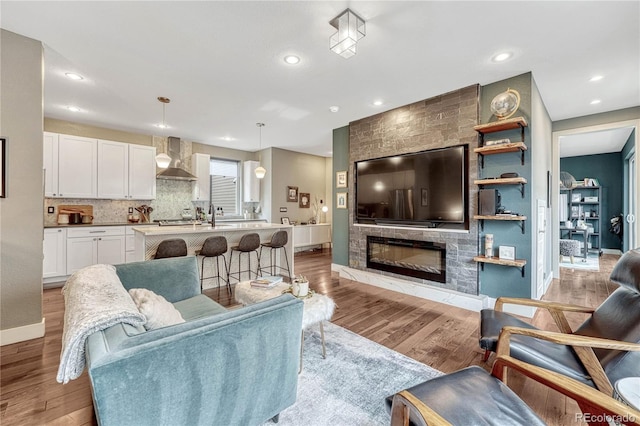 living room featuring recessed lighting, light wood-type flooring, baseboards, and a fireplace