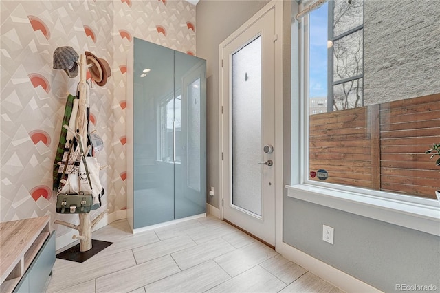 bathroom featuring a shower, baseboards, and wallpapered walls