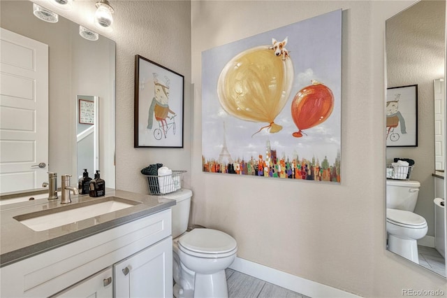 bathroom with vanity, toilet, and baseboards