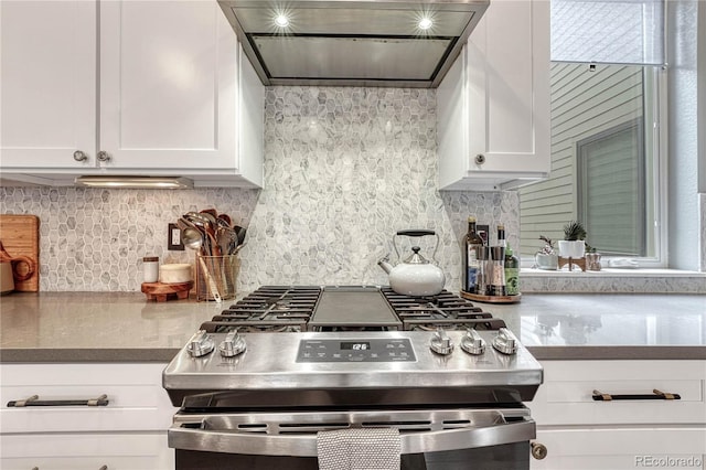 kitchen featuring decorative backsplash, extractor fan, stainless steel range with gas stovetop, and white cabinetry