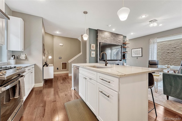 kitchen featuring a sink, a kitchen bar, wood-type flooring, and appliances with stainless steel finishes