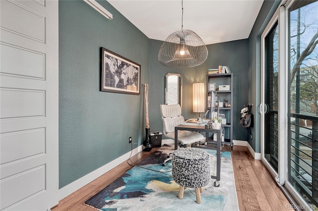 office area with arched walkways, a textured wall, baseboards, and wood finished floors