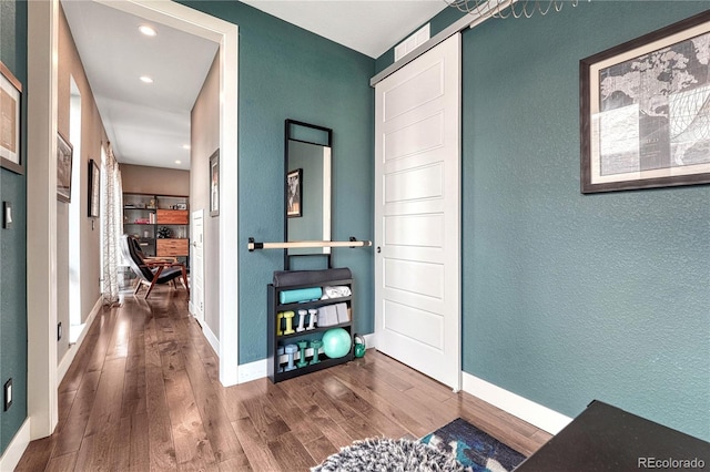 foyer featuring baseboards, wood finished floors, and a textured wall