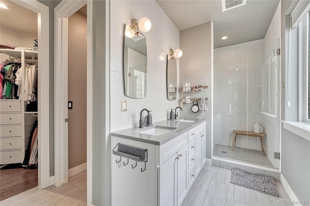 full bath with a spacious closet, visible vents, a shower stall, and a sink