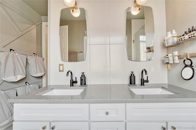 bathroom with double vanity, a textured wall, and a sink