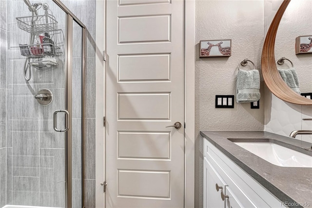 bathroom featuring a shower stall, vanity, and a textured wall