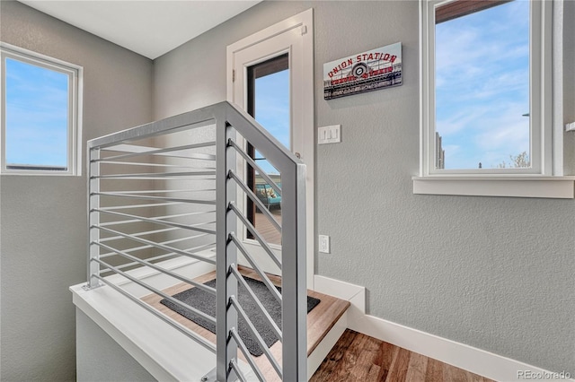 staircase with baseboards, a textured wall, and wood finished floors