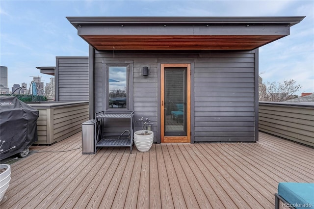 wooden deck with grilling area and a view of city