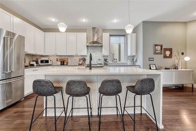 kitchen with dark wood-style floors, decorative backsplash, high end fridge, and wall chimney exhaust hood