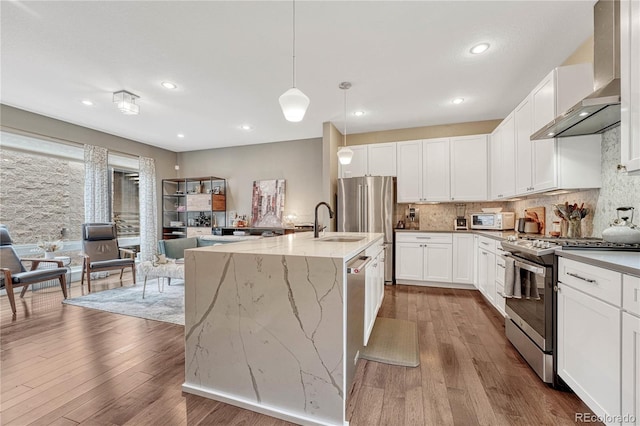 kitchen with wall chimney exhaust hood, wood finished floors, backsplash, and stainless steel gas range oven