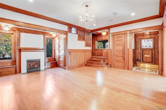 unfurnished living room featuring hardwood / wood-style flooring, a wealth of natural light, ornamental molding, and a notable chandelier