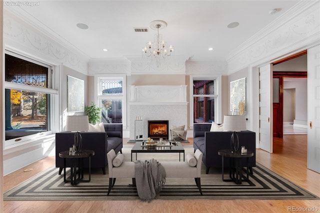 living room with light hardwood / wood-style floors, ornamental molding, and an inviting chandelier