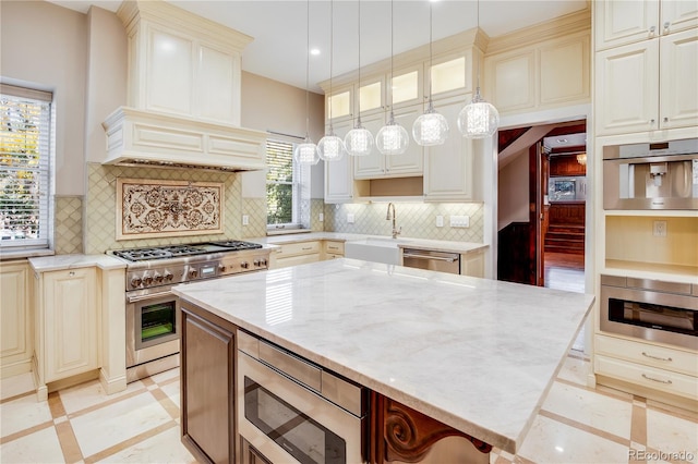 kitchen with sink, light stone counters, backsplash, decorative light fixtures, and appliances with stainless steel finishes