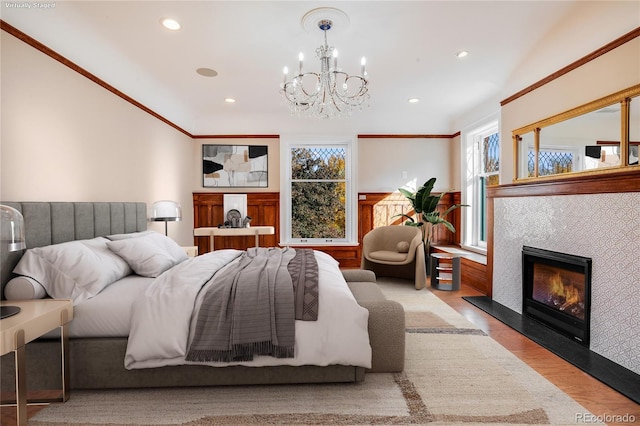 bedroom with a notable chandelier, light hardwood / wood-style floors, ornamental molding, and a fireplace