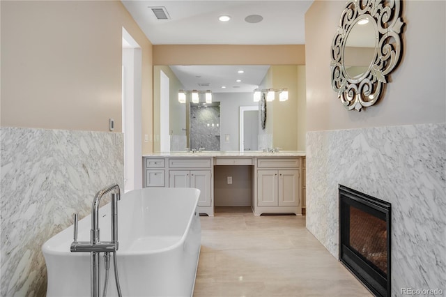 bathroom with a tub, vanity, and tile walls