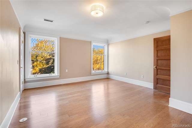 empty room with crown molding and light wood-type flooring