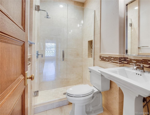 bathroom with tile patterned flooring, a shower with door, tile walls, and toilet