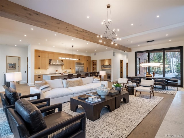 living room featuring an inviting chandelier, beam ceiling, and light wood-type flooring