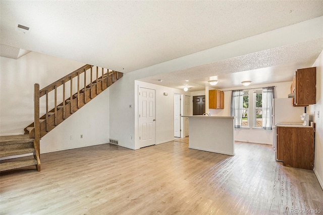 1545 S Ouray Cir Unit B, Aurora, CO 80017 - kitchen with light wood-style floors, brown cabinetry, open floor plan, light countertops, and a peninsula