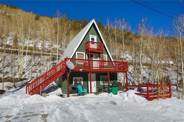 snow covered property featuring a deck and stairway