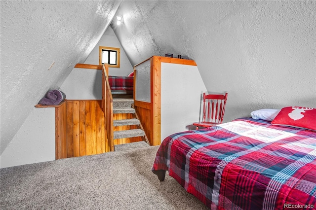 bedroom with carpet, vaulted ceiling, a textured ceiling, and a textured wall