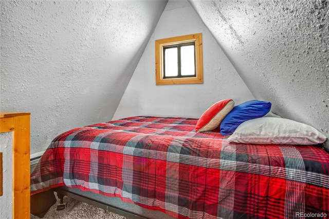 bedroom with vaulted ceiling and a textured wall